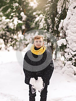 Teenage boy have fun and plays with snow in the winter forest. Clothes in color 2021. vertical
