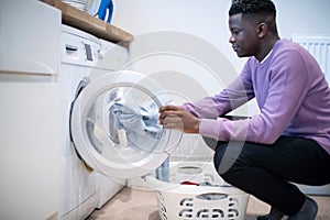 Teenage Boy Helping With Domestic Chores At Home Emptying Washing Machine