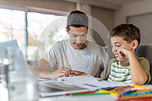 Teenage boy helping his younger brother doing homework