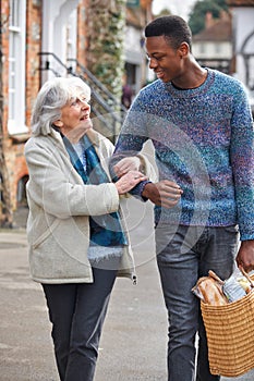 Teenage Boy Helping Senior Woman To Carry Shopping