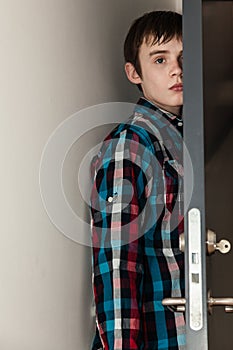 Teenage Boy Hiding Behind Open Door in Home