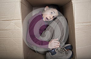 Teenage boy hiding in cardboard box