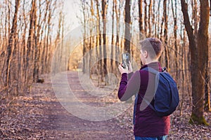 Teenage boy hiking and taking photos of the beautiful forest