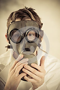 Teenage boy holding gas mask on face
