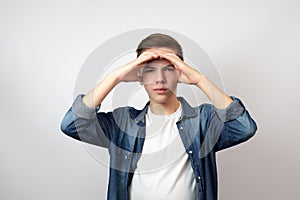 Teenage boy holding hands on his forehead and looking far away to the future