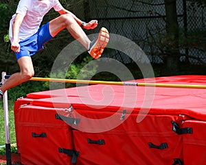 Teenage boy jumping over a high jump bar like he is hurdling