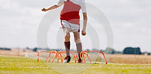 Teenage boy jumping over hurdles. Young soccer athlete practicing strength and agility skills at soccer school academy. Soccer