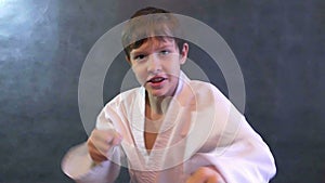 Teenage boy in kimono karate fight hands waving