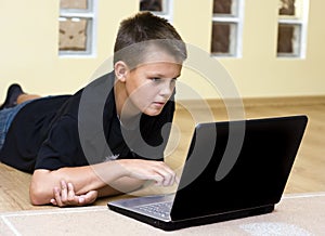 Teenage boy and laptop on floor