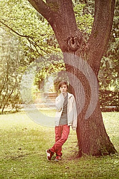 Teenage boy leaning against a tree