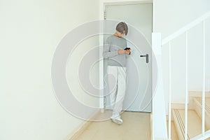 Teenage boy leaning on door and using smart phone. Kid using app to type text message, communicate with friends, family
