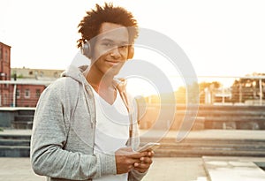 Teenage Boy Listening To Music And Using Phone In Urban Setting