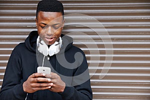 Teenage Boy Listening To Music And Using Phone In Urban Setting