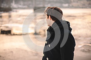 Teenage boy looking on river while standing outdoors in winter