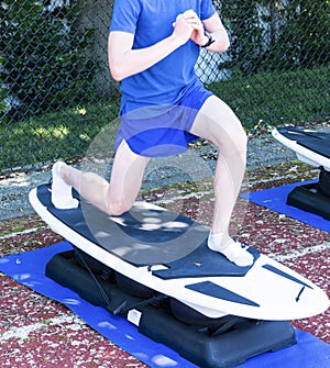 Teenage boy lunging on a portable surfboard machine