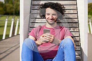 Teenage Boy Outdoors On College Campus Checking Text Messages Or Social Media Or Streaming Movie Or Film