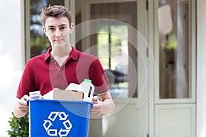 Portrait Of Teenage Boy Outside House Carrying Recycling Bin