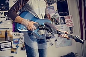 Teenage boy playing an electric guitar in a bedroom hobby and mu