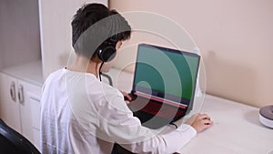 Teenage boy playing game on his pc computer in white room. Gamer capture video on web camera on laptop and phone on