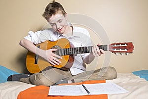 Teenage boy playing guitar in her bedroom