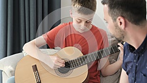 A teenage boy playing guitar at home in a family circle. Teen boy learning to play the guitar