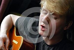 Teenage boy playing guitar and singing