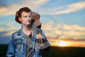 Teenage boy playing guitar at sunset