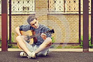 Teenage Boy plays an acoustic guitar