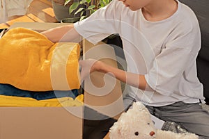 Teenage boy preparing itemsfor charity and packing into donation box at home. Donations for charity, help low income