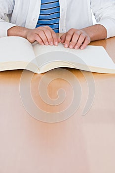 Teenage boy reading a braille book