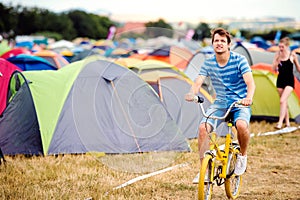 Dospievajúci chlapec jazdiaci na žltom bicykli na letnom hudobnom festivale