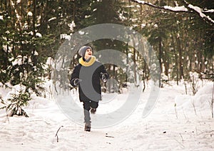 Teenage boy runs through the winter forest