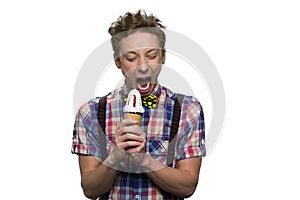 Teenage boy`s struggling with himself to bite cold ice-cream.