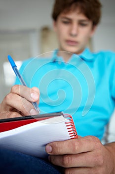 Teenage boy sat writing in notebook