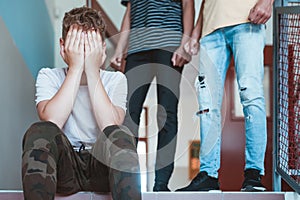 Teenage boy sitting alone at school, bullying among children concept