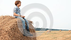 Teenage boy sitting on haystack, talking and screaming