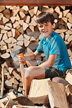 Teenage boy sitting on heap of firewood