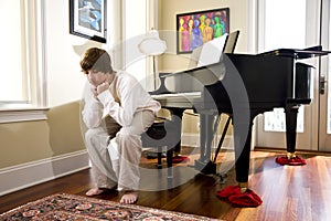 Teenage boy sitting on piano bench looking down