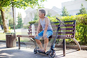 teenage boy sitting with a scooter on the bench .