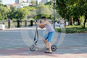 Teenage boy sitting with a scooter on the bench .