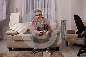 Teenage boy sitting on sofa playing computer games.