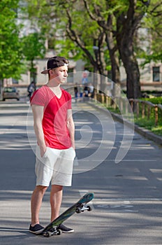 Teenage boy with skateboard standing in middle of street