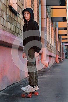 Teenage boy skateboarding on city street at sunset