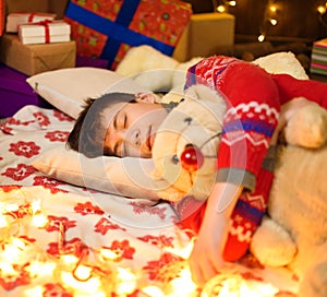 Teenage boy sleeping in new year or christmas decoration. Holiday lights, gifts and christmas tree decorated with toys