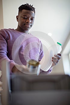 Teenage Boy Sorting Recycling Into Kitchen Bin At Home