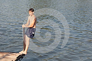 Teenage boy standing on the edge of wooden dock