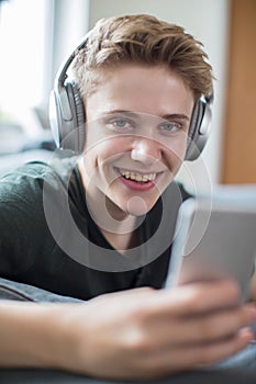 Teenage Boy Streaming Music From Mobile Phone To Wireless Headphones