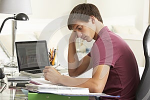 Teenage Boy Studying At Desk In Bedroom