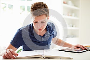 Teenage Boy Studying Using Digital Tablet At Home