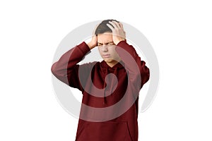 Teenage boy suffering from headache or migraine, isolated on white. Young guy wincing in pain holding head in hands